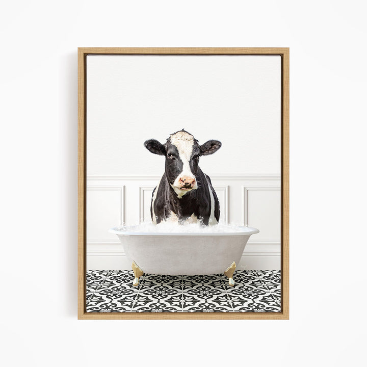 A black and white cow is sitting in a white bathtub filled with water, creating a whimsical and humorous scene.