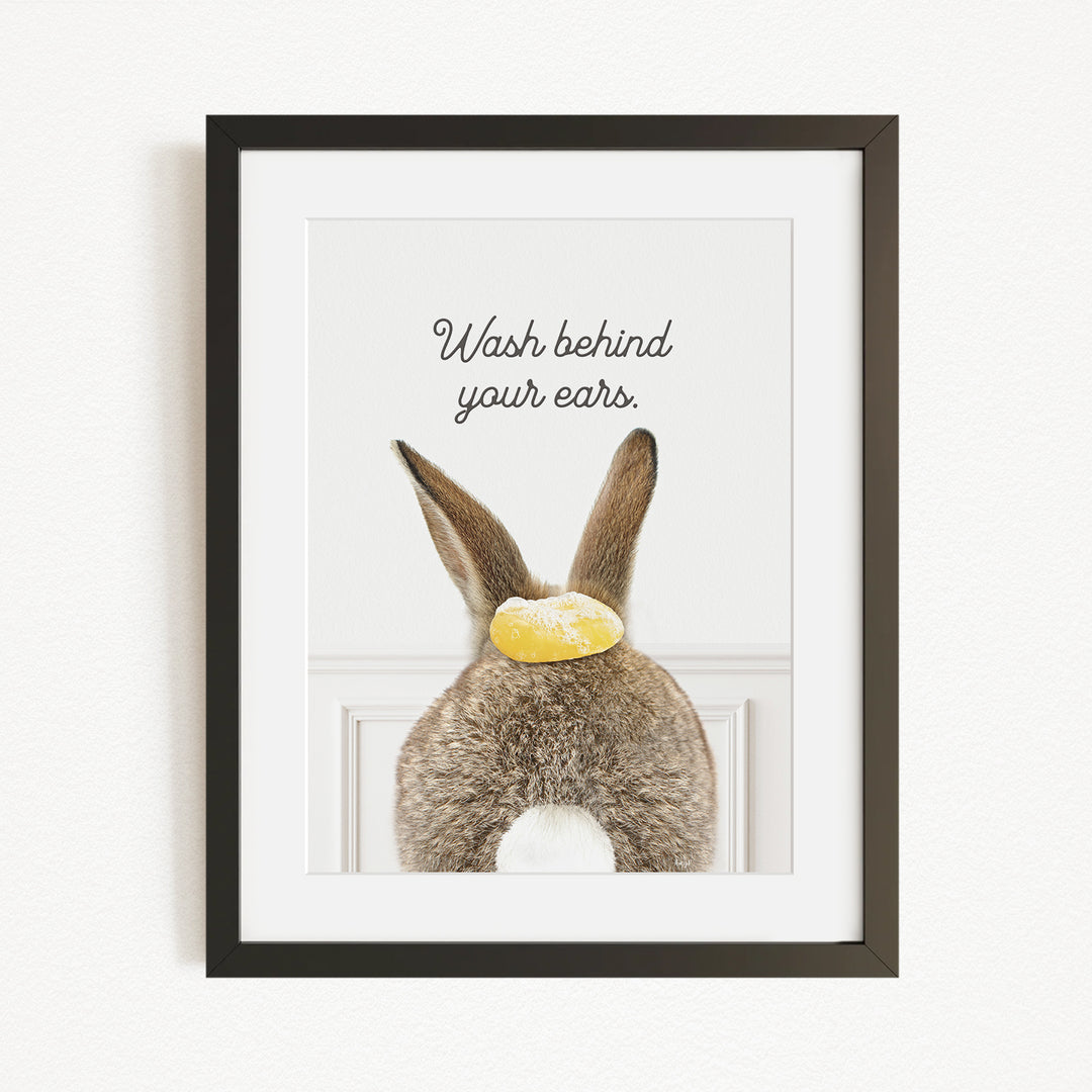 A framed image of a rabbit's back with the text "Wash behind your ears" written above it.