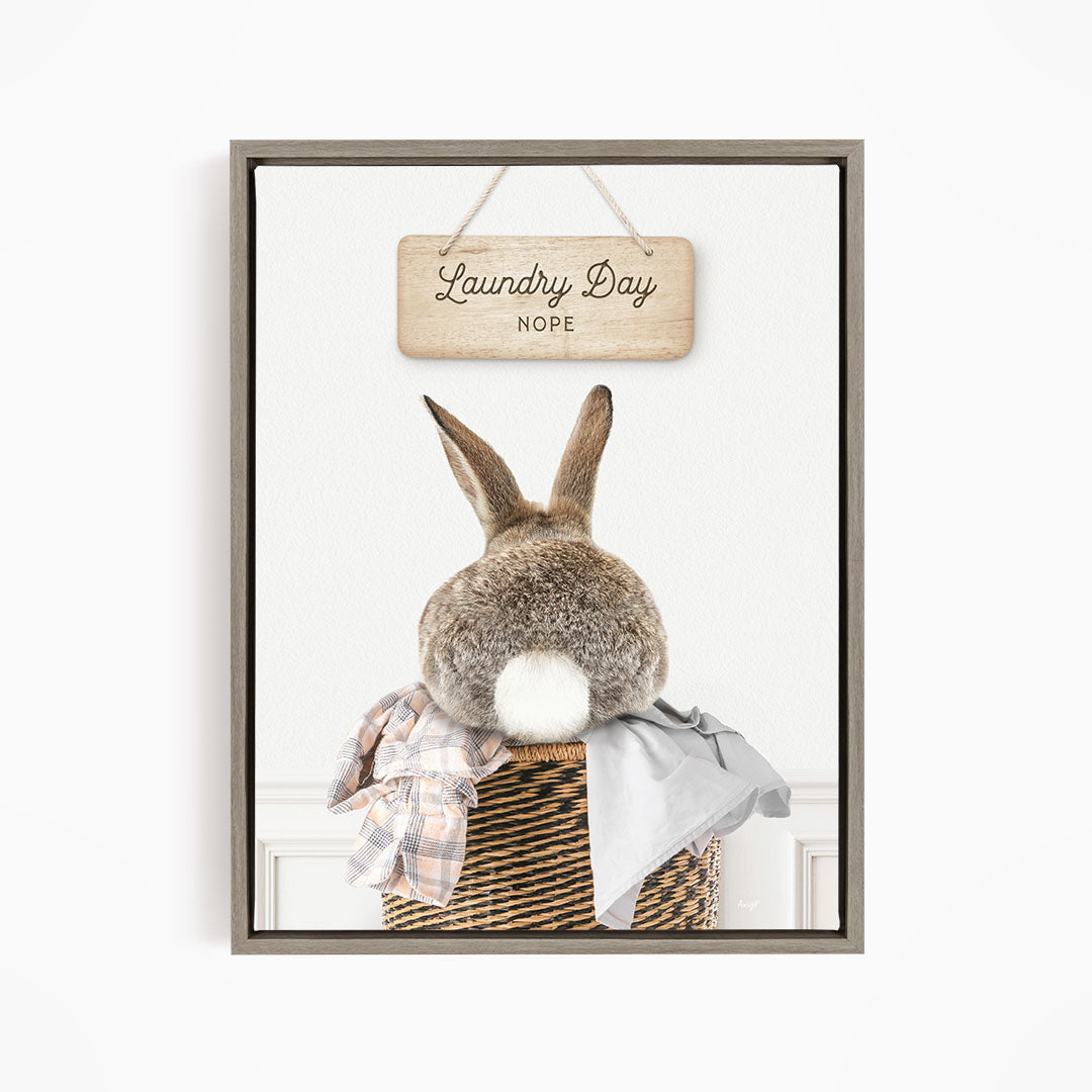 A wooden sign with the text "Laundry Day NOPE" hangs above a wicker basket containing a plaid blanket and a gray shirt.