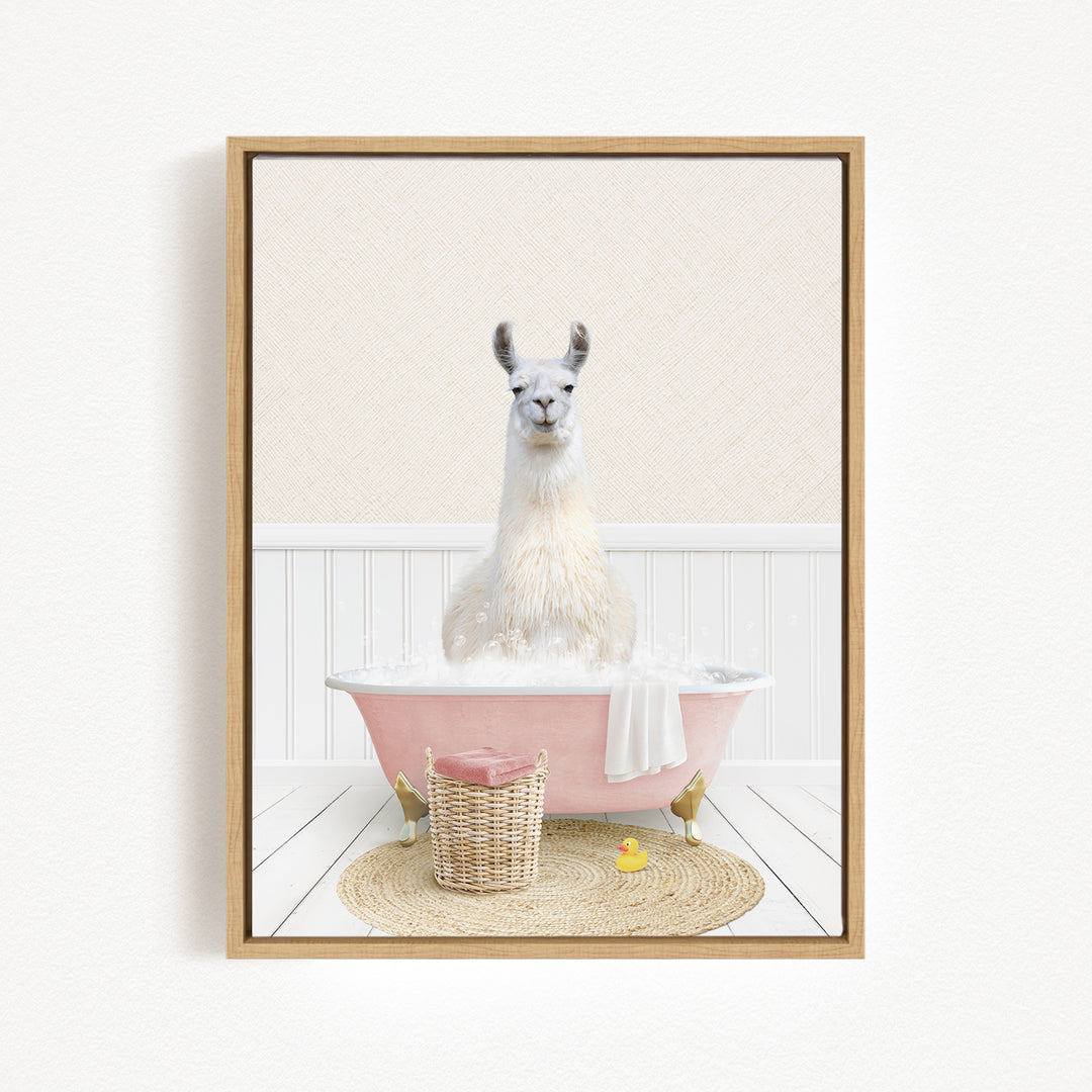 A white llama sitting in a pink bathtub filled with bubbles, surrounded by a basket of bath toys and a yellow rubber duck.