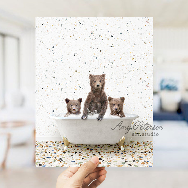 a hand holding a card with three bears in a bathtub