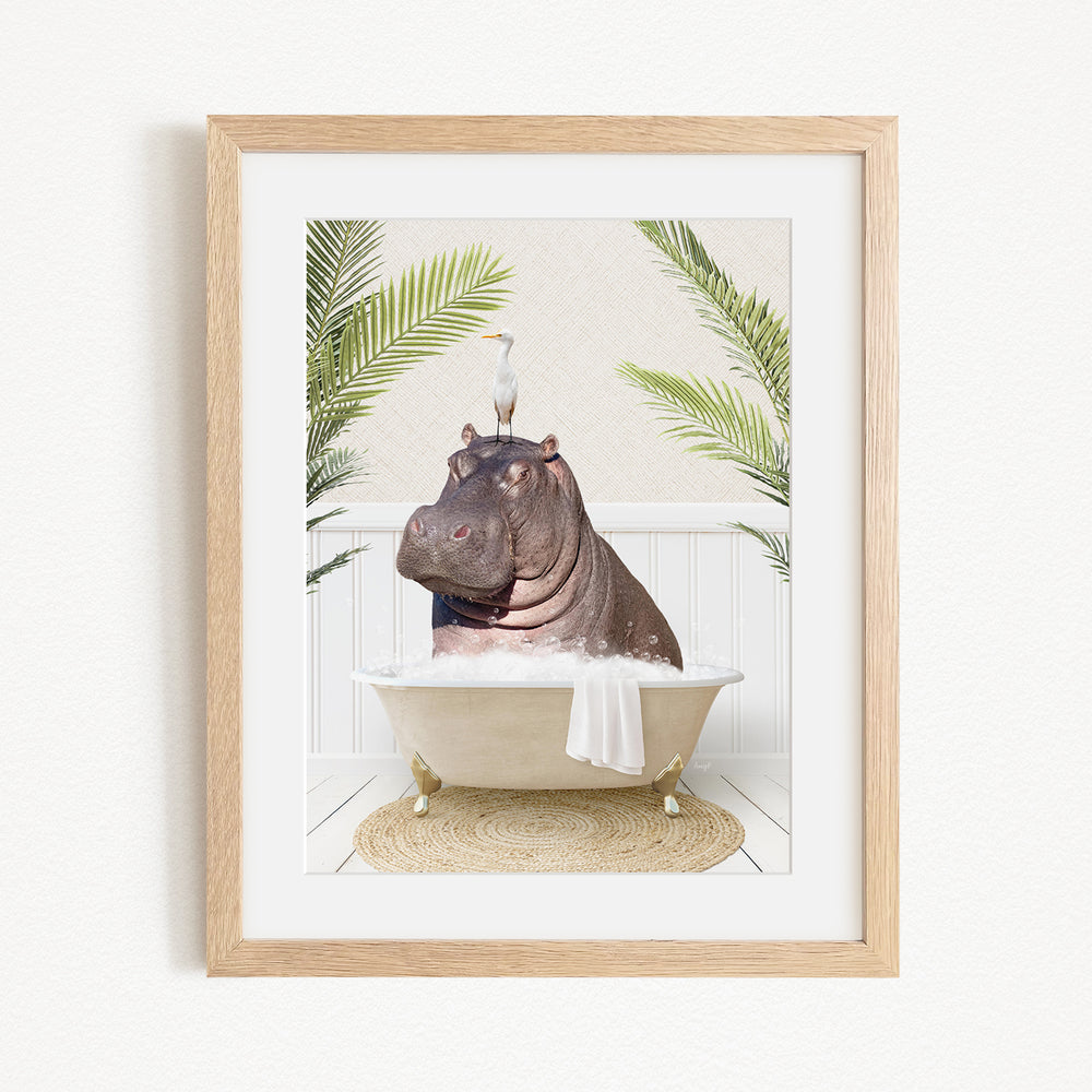 A framed image depicting a hippopotamus sitting in a bathtub, with a bird perched on its head.
