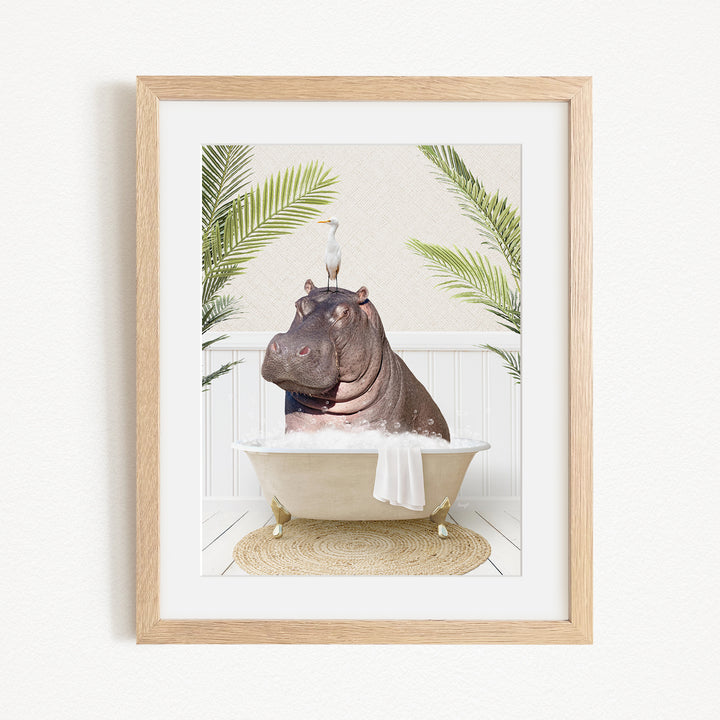 A framed image depicting a hippopotamus sitting in a bathtub, with a bird perched on its head.