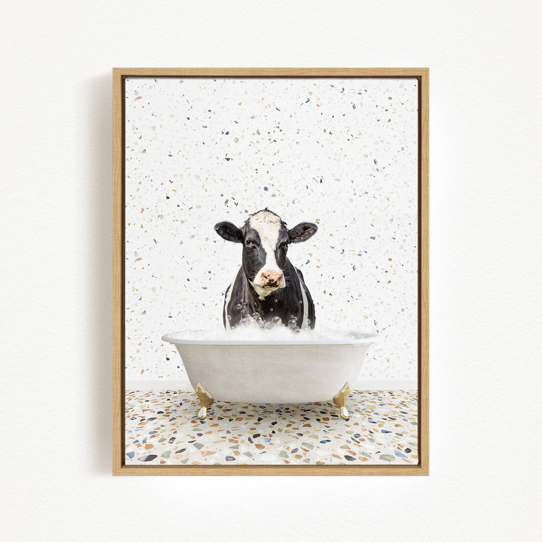 A black and white cow is sitting in a white bathtub filled with water, creating a whimsical and playful scene.