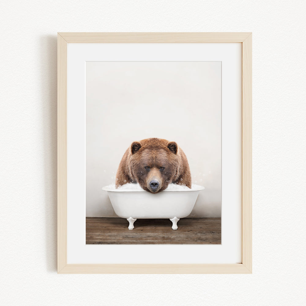 A brown bear is sitting in a white bathtub, appearing to be enjoying a relaxing bath.