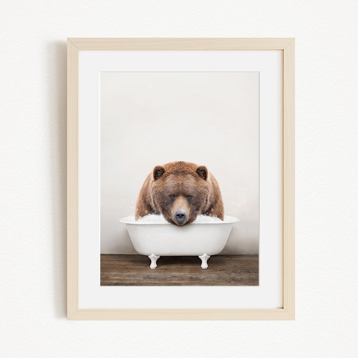 A brown bear is sitting in a white bathtub, appearing to be enjoying a relaxing bath.