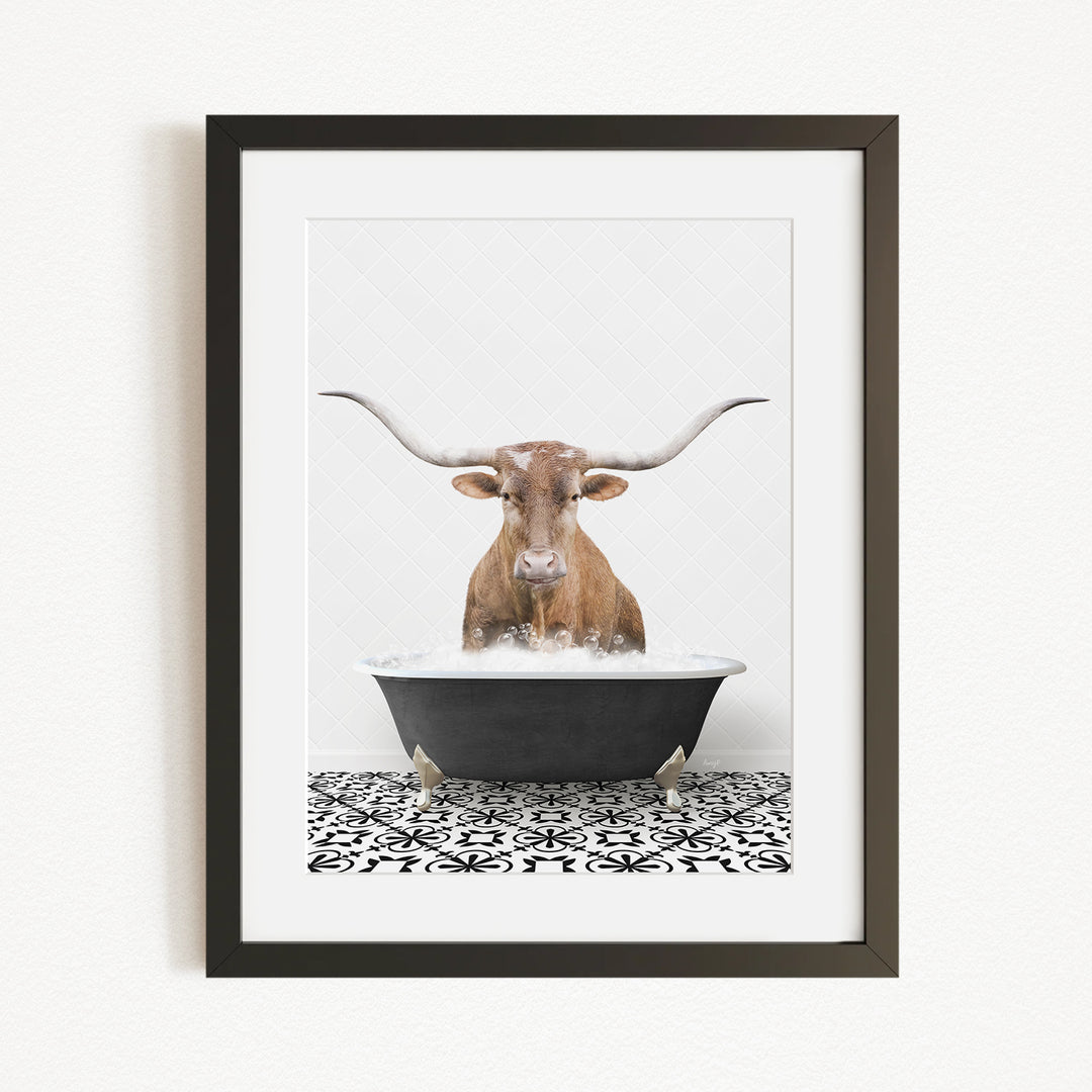 A framed image depicting a brown cow with large horns sitting in a bathtub filled with water.