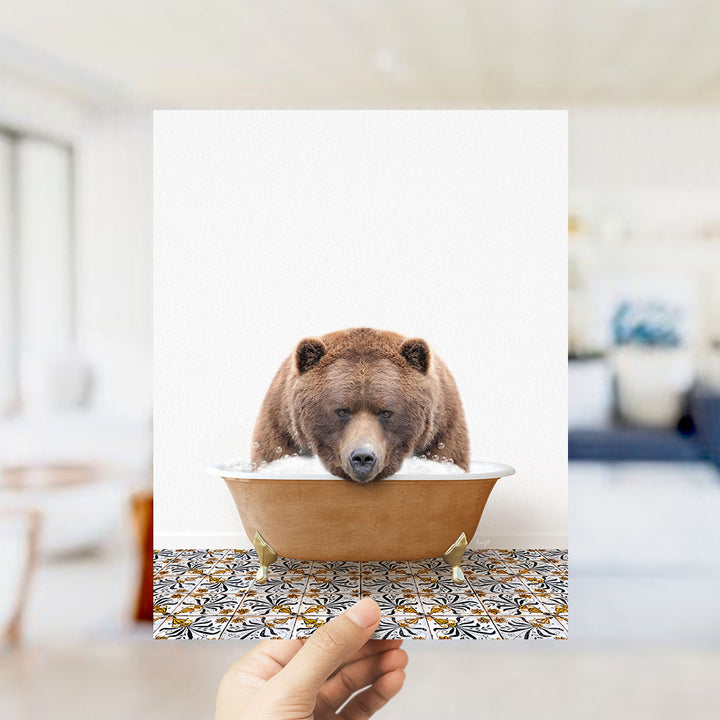 A brown bear sitting in a bathtub filled with water, with a hand holding up the image to show it.