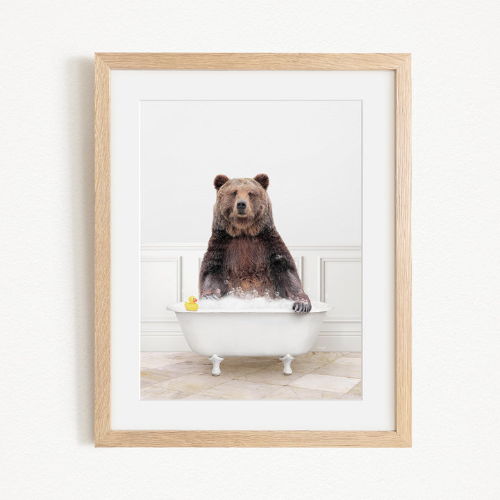 A brown bear sitting in a white bathtub, with a yellow rubber duck floating in the water.