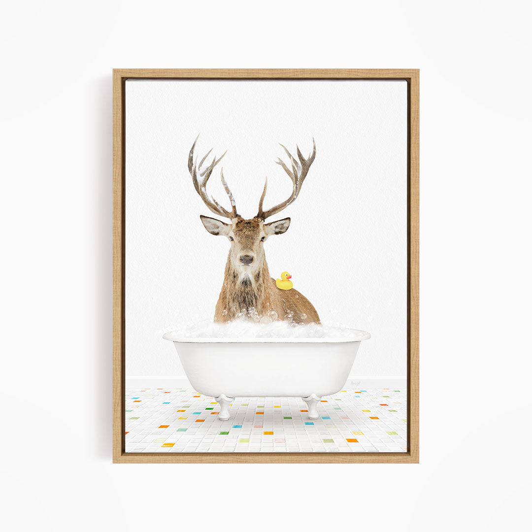 A deer with large antlers is sitting in a white bathtub filled with bubbles, with a yellow duck perched on its back.