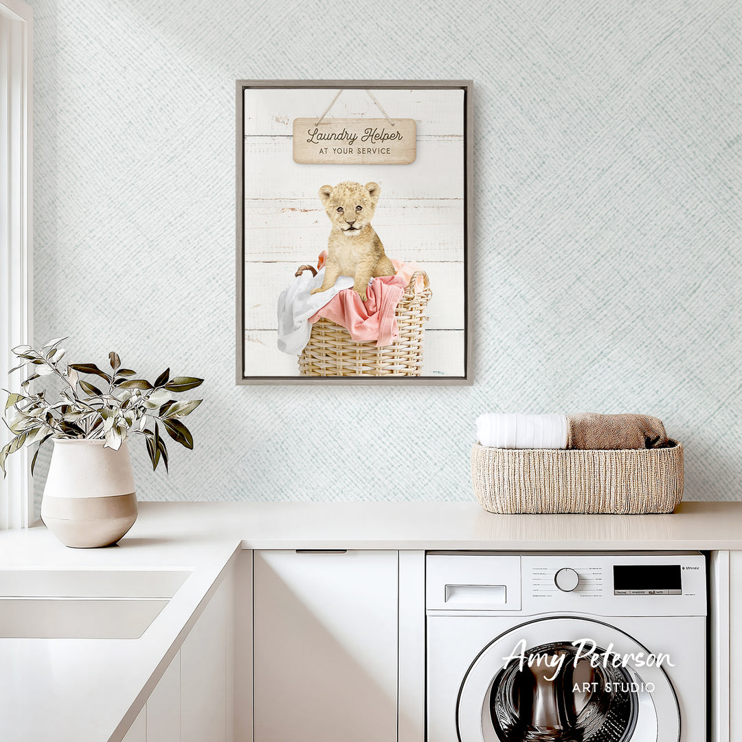 a laundry room with a framed poster of a baby lion in a basket, a white washing machine, and a potted plant on the counter.