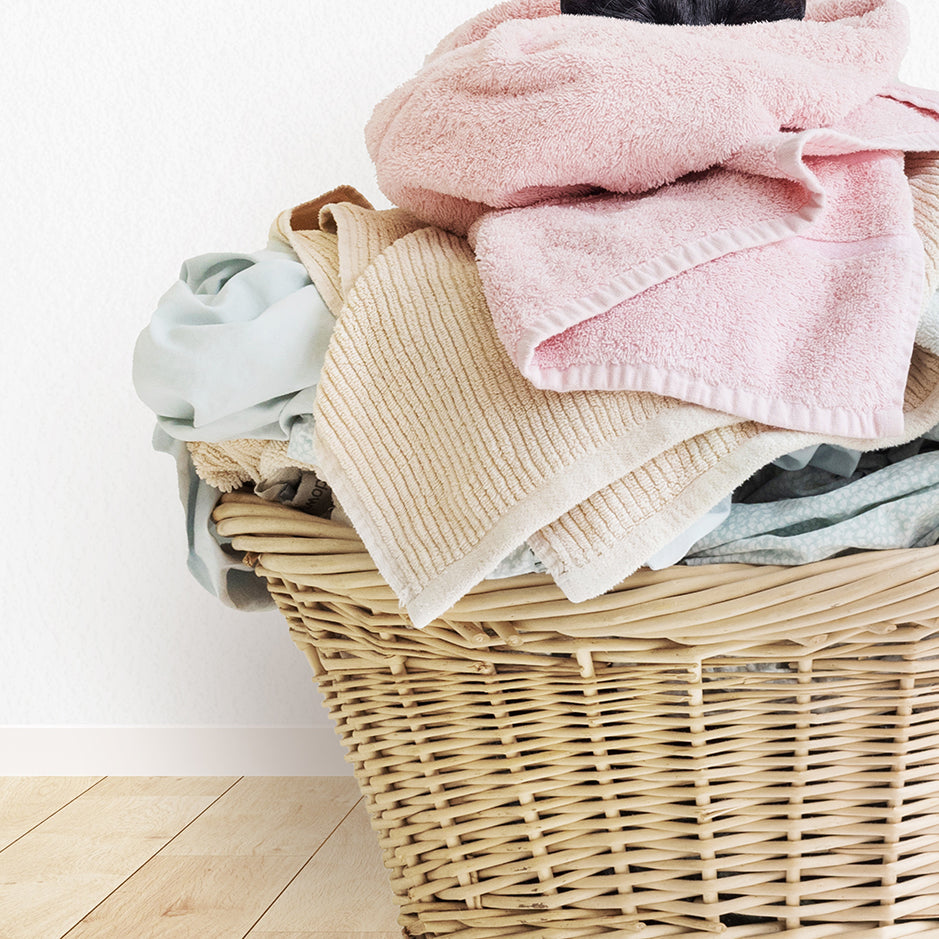 a wicker basket filled with clothes on a wooden floor