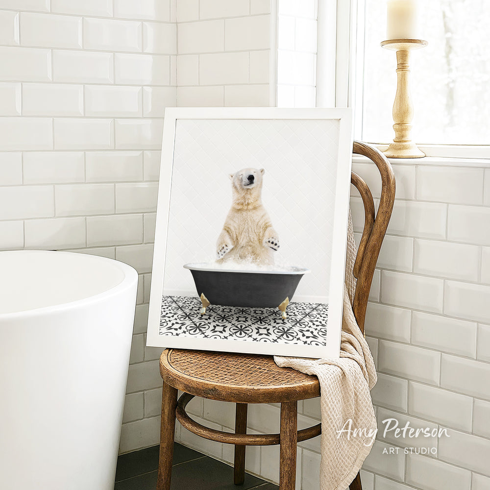 A framed image of a polar bear sitting in a bathtub is displayed on a wooden chair in a bathroom setting.