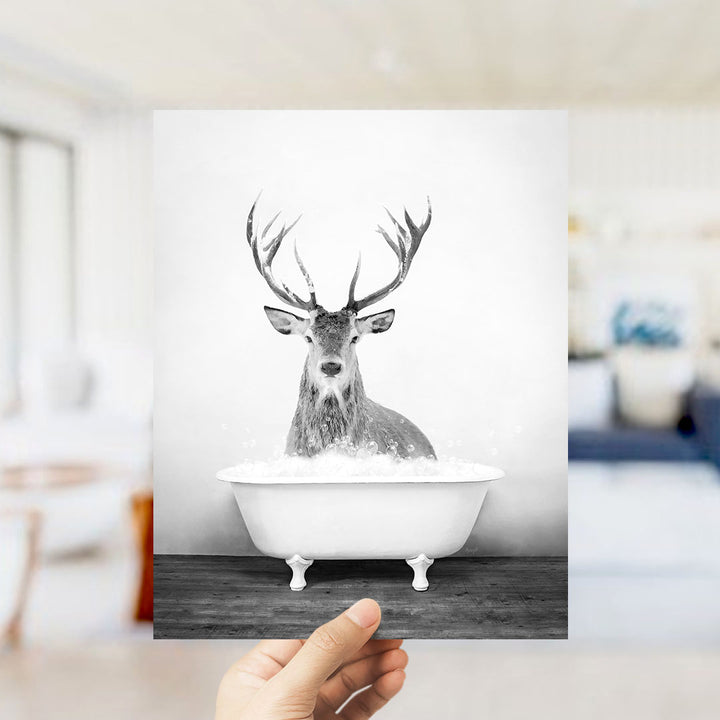 A black and white photograph of a deer with large antlers sitting in a bathtub filled with water.