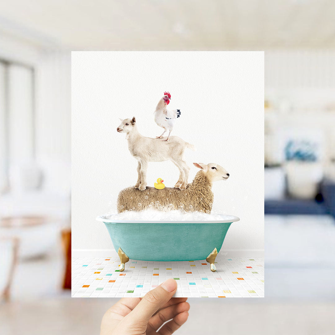 A hand holds up a framed image depicting a goat standing on a sheep's back while a chicken sits on top of a sheep in a bathtub.
