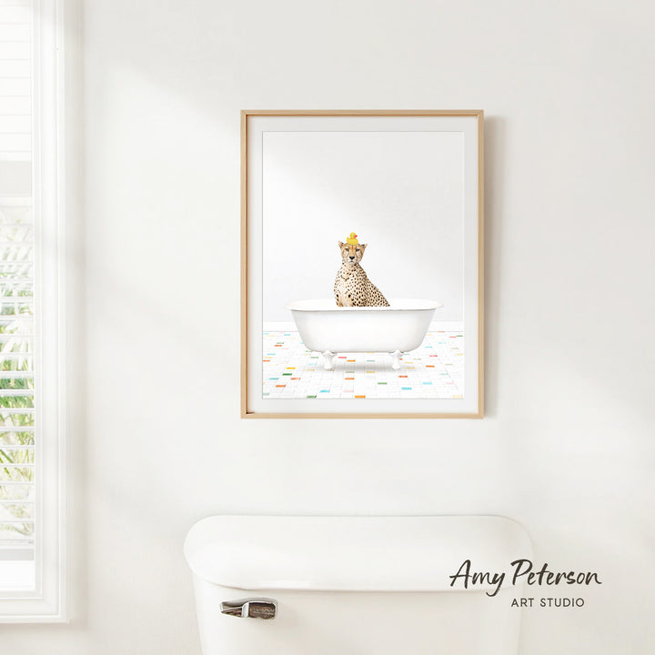 A framed print of a cheetah sitting in a white bathtub is hanging on a white wall in a bathroom.