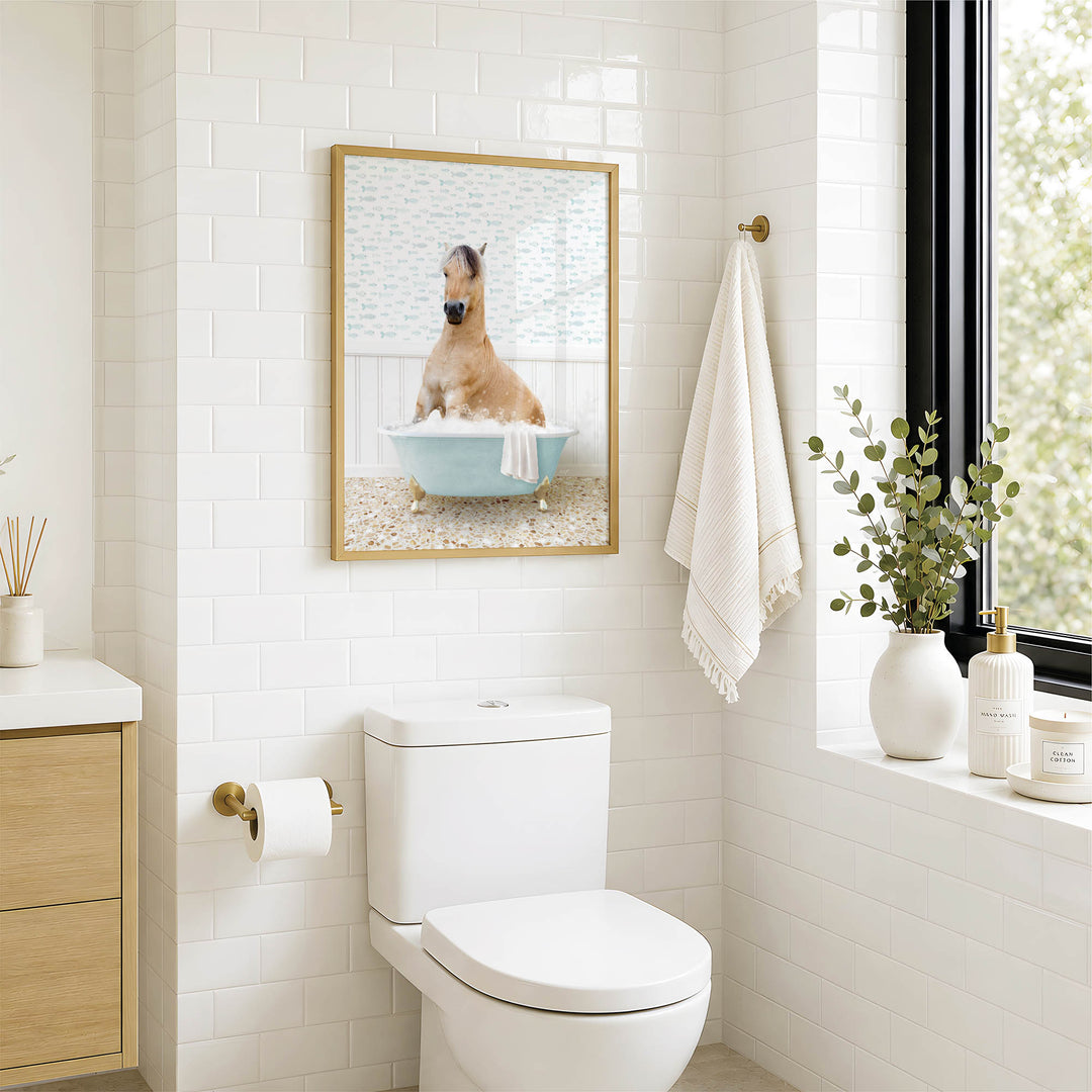 A bathroom with a white toilet, a framed picture of a dog sitting in a bathtub, and a window with greenery outside.