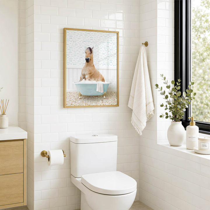 A bathroom with a white toilet, a framed picture of a dog sitting in a bathtub, and a window with greenery outside.