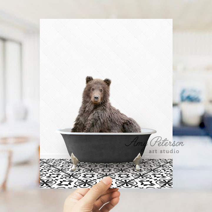 a hand holding up a card with a bear in a bathtub