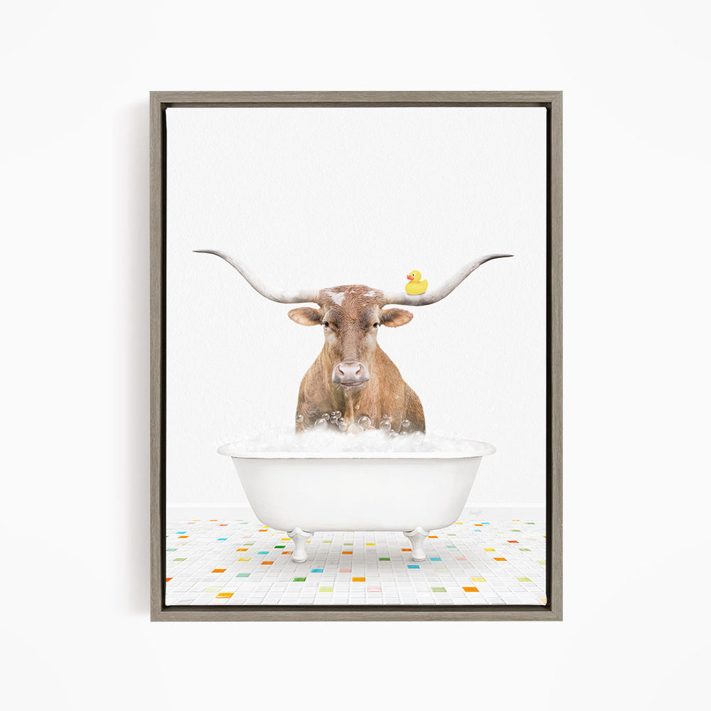 A brown cow with large horns is sitting in a white bathtub filled with bubbles, with a yellow rubber duck floating on the water.