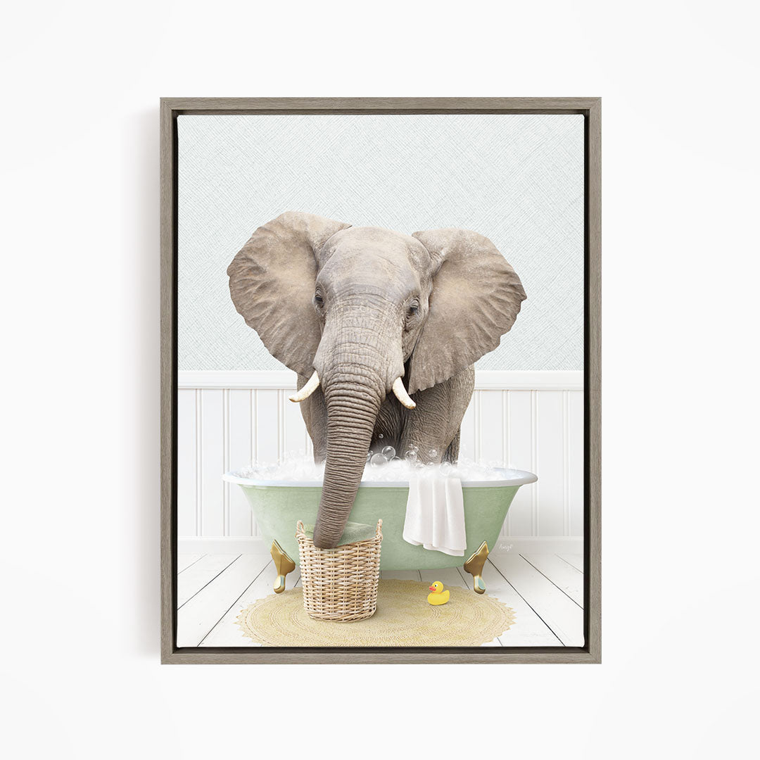 A gray elephant is standing in a green bathtub filled with water, surrounded by a yellow rubber duck and a basket.