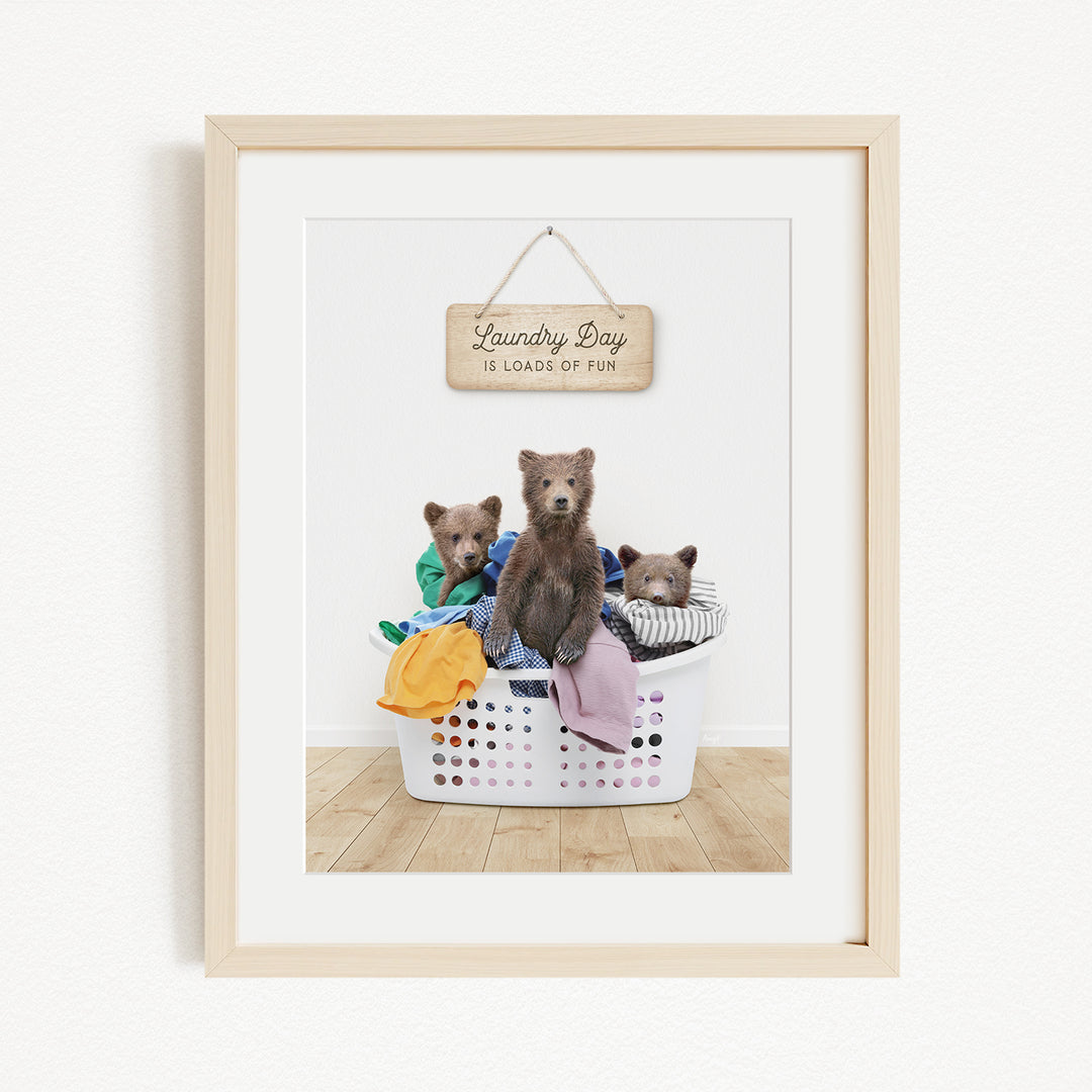 A framed image depicting three bears sitting in a laundry basket, with a sign above them that reads "Laundry Day is loads of fun".
