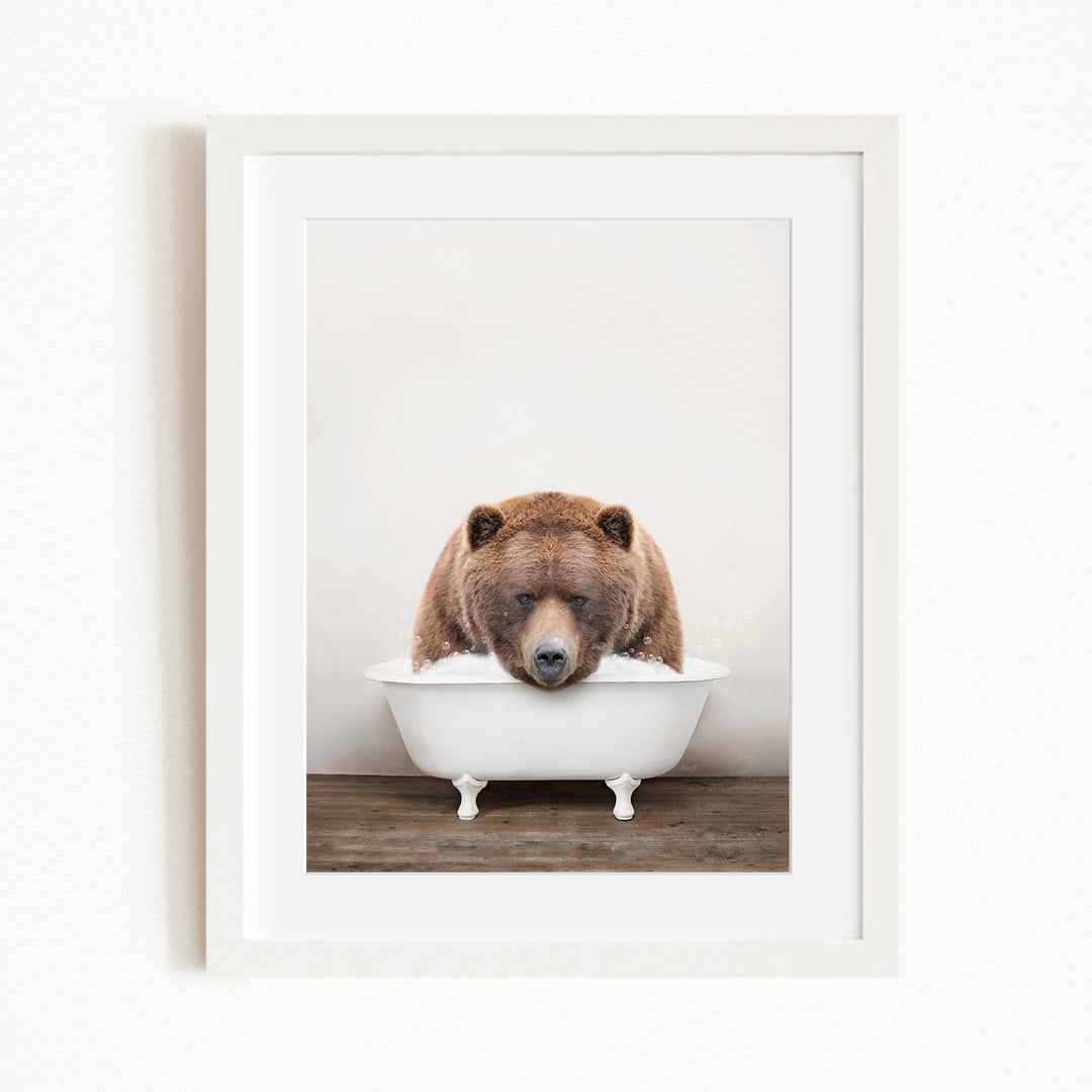 A brown bear is sitting in a white bathtub filled with water, appearing to be enjoying a relaxing bath.