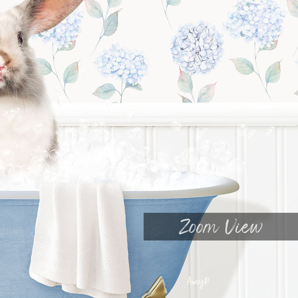 A white rabbit is sitting in a blue bathtub filled with bubbles, with a floral wallpaper in the background.