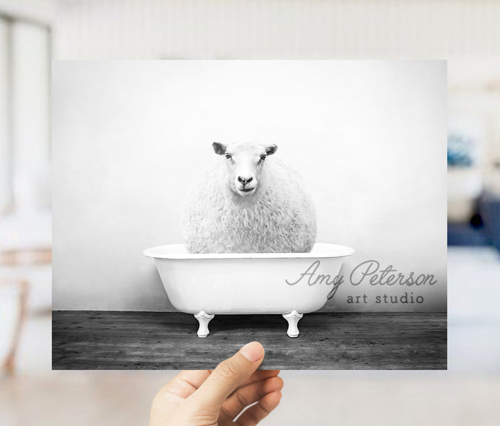 a person holding up a card with a sheep in a bathtub