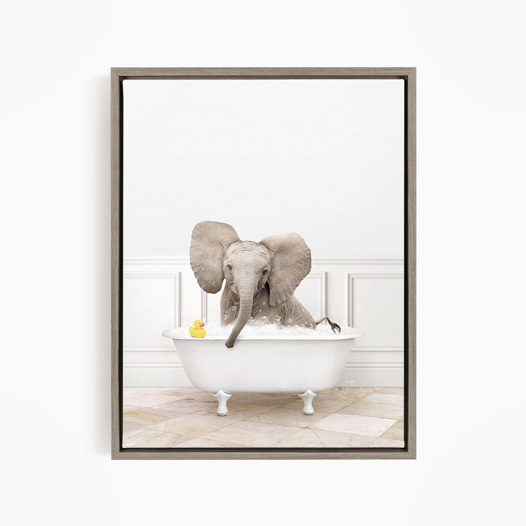 A gray elephant is sitting in a white bathtub, with a yellow rubber duck floating on the water.