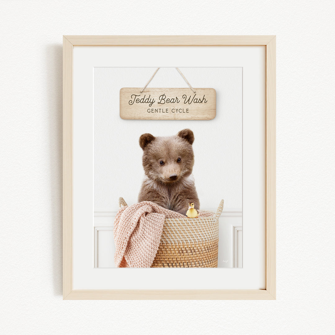 A framed image of a teddy bear sitting in a woven basket, with a sign above it that reads "Teddy Bear Wash Gentle Cycle".