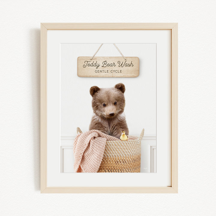 A framed image of a teddy bear sitting in a woven basket, with a sign above it that reads "Teddy Bear Wash Gentle Cycle".