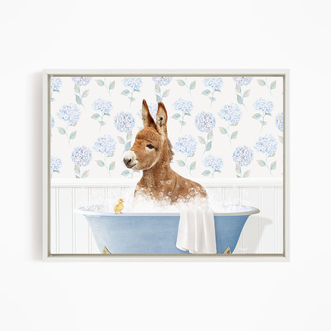 A brown dog is sitting in a blue bathtub filled with bubbles, with a yellow duck sitting on the edge of the tub.