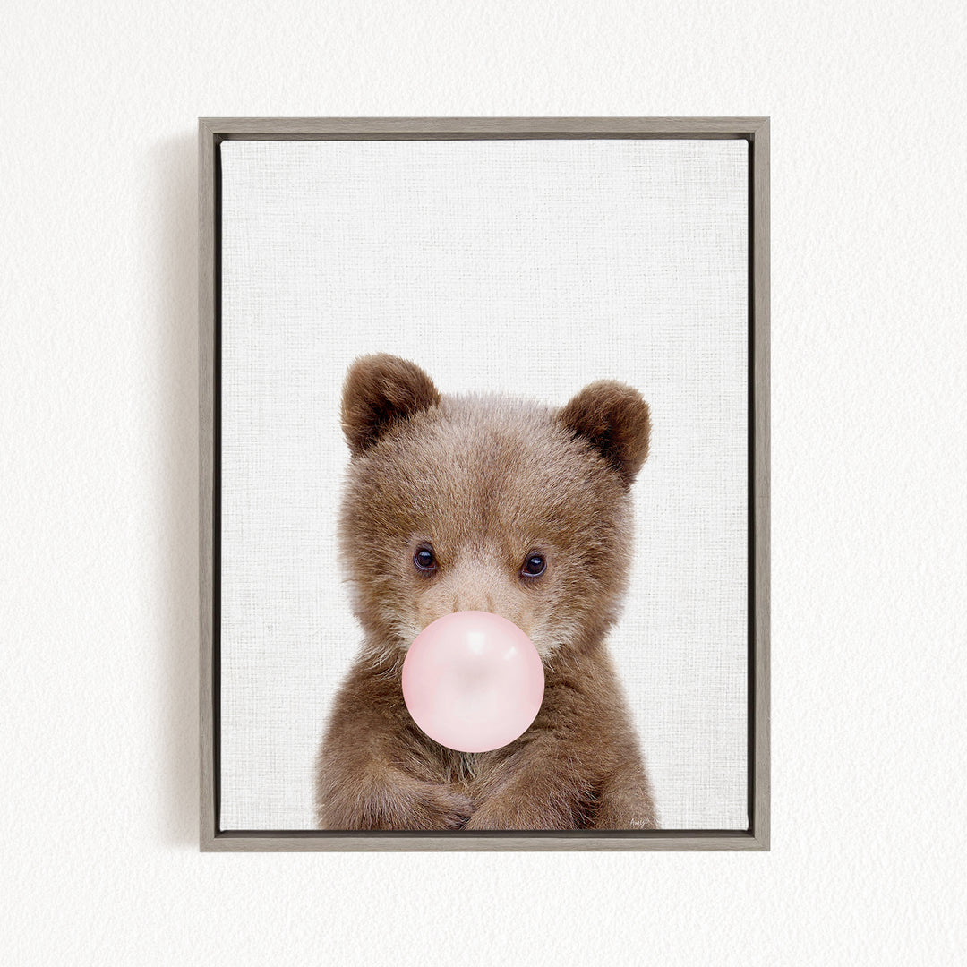 A cute brown bear is blowing a bubble with a pink bubble gum bubble.