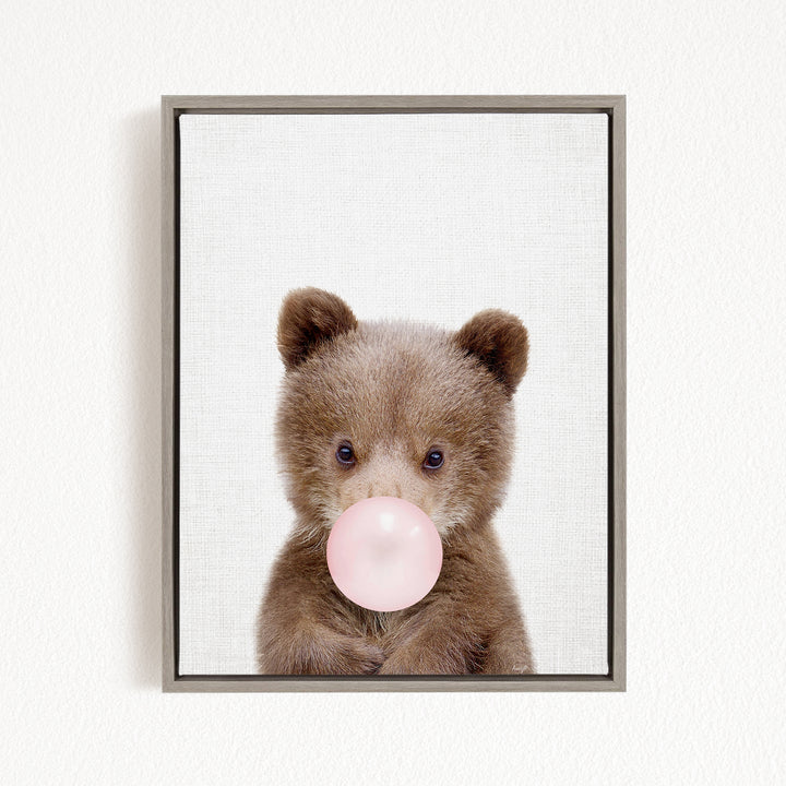 A cute brown bear is blowing a bubble with a pink bubble gum bubble.