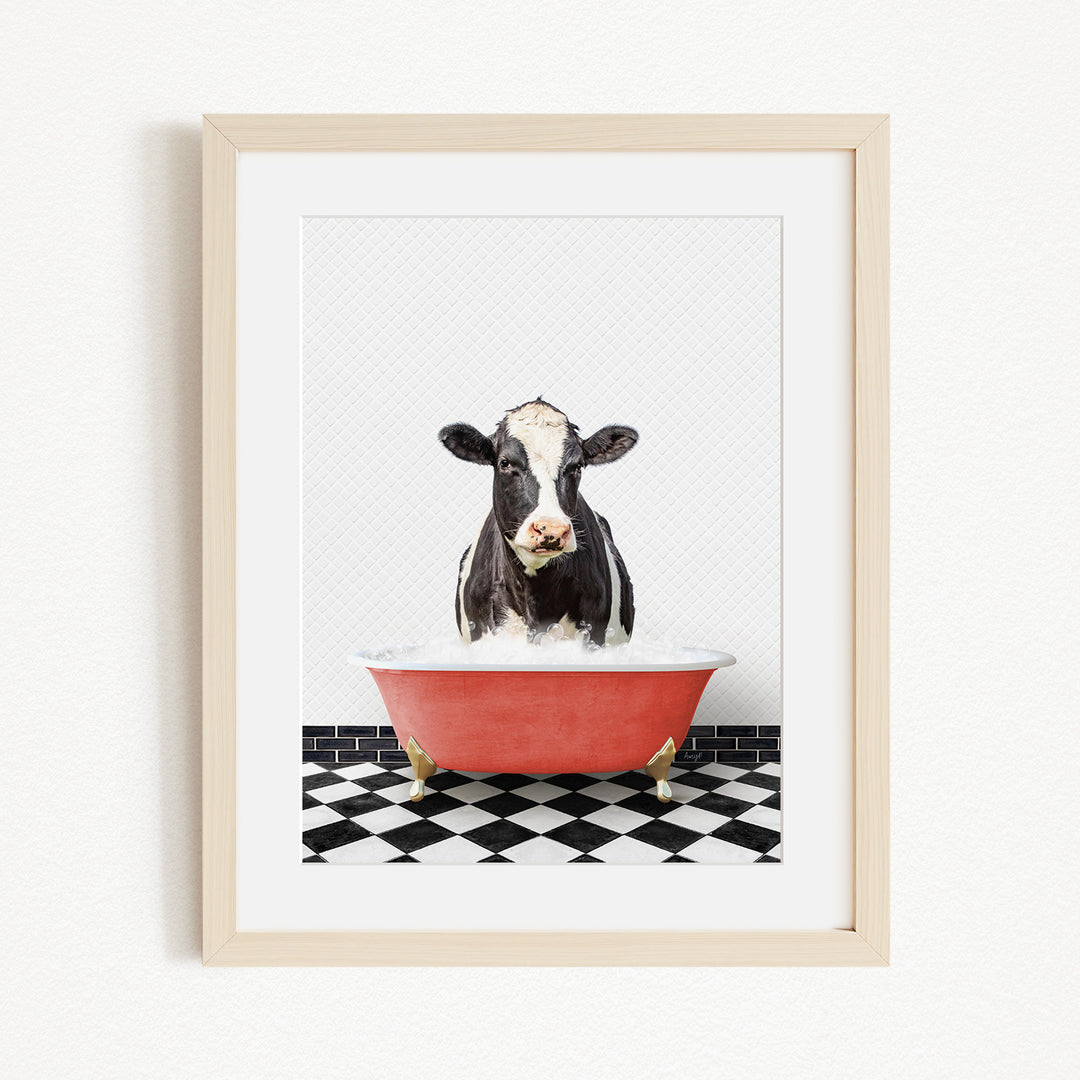 A black and white cow is sitting in a red bathtub filled with water, creating a whimsical and humorous scene.