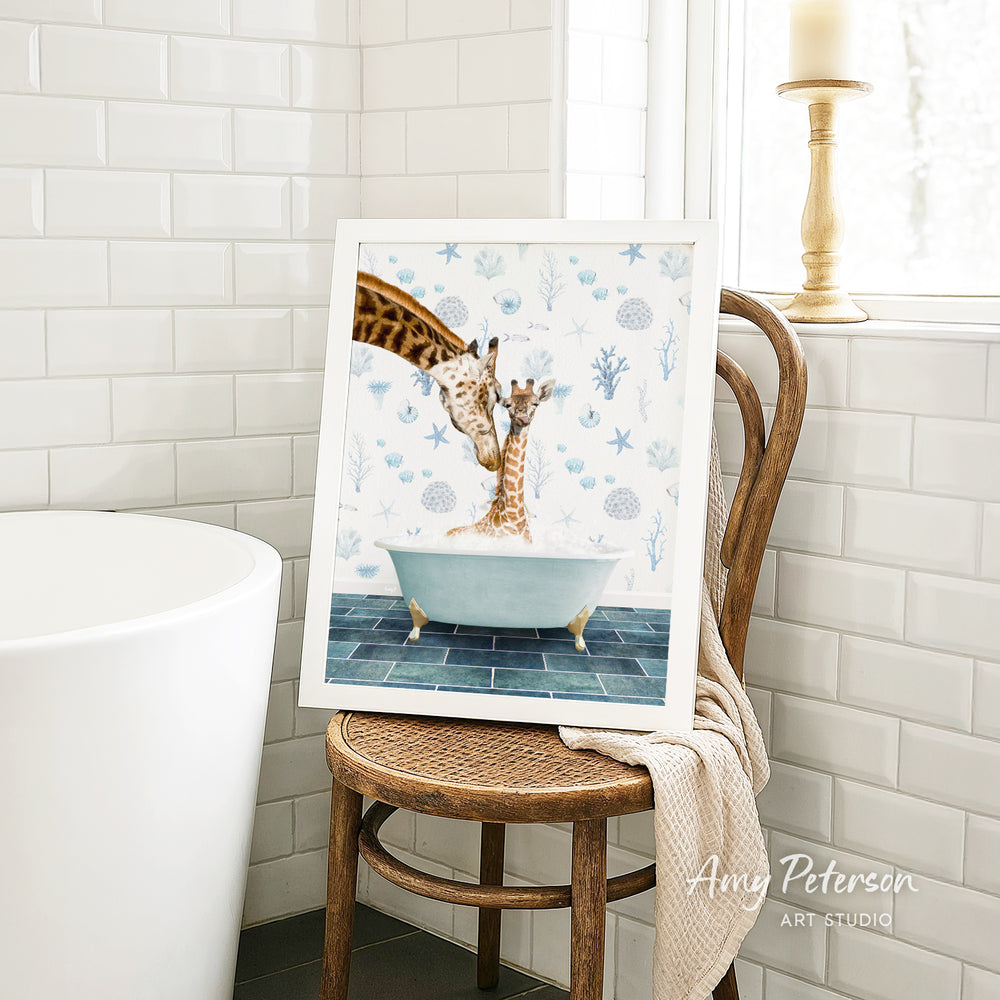 A framed painting of two giraffes sitting in a bathtub, surrounded by blue and white floral patterns, is displayed on a wooden chair in a bathroom setting.