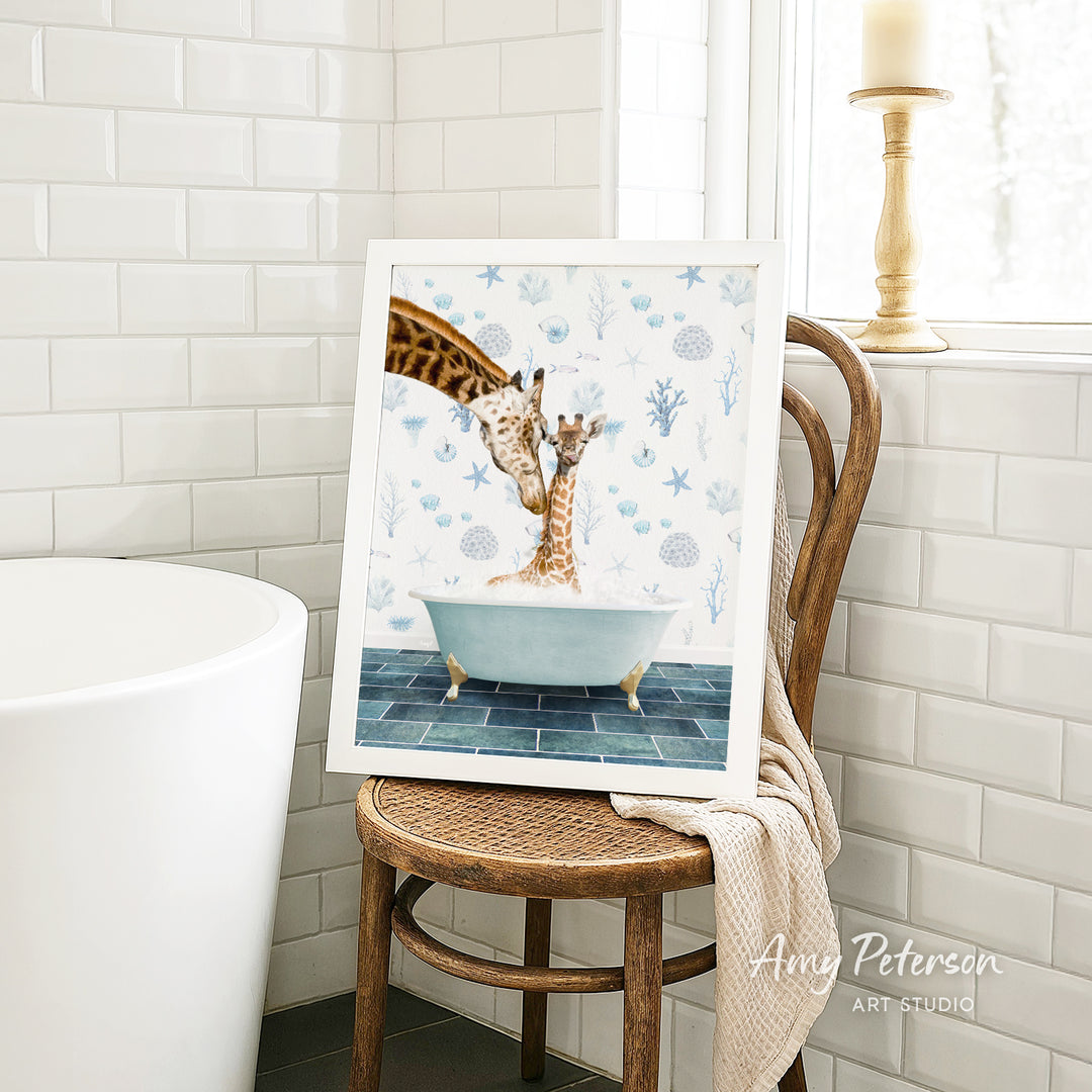 A framed painting of two giraffes sitting in a bathtub, surrounded by blue and white floral patterns, is displayed on a wooden chair in a bathroom setting.