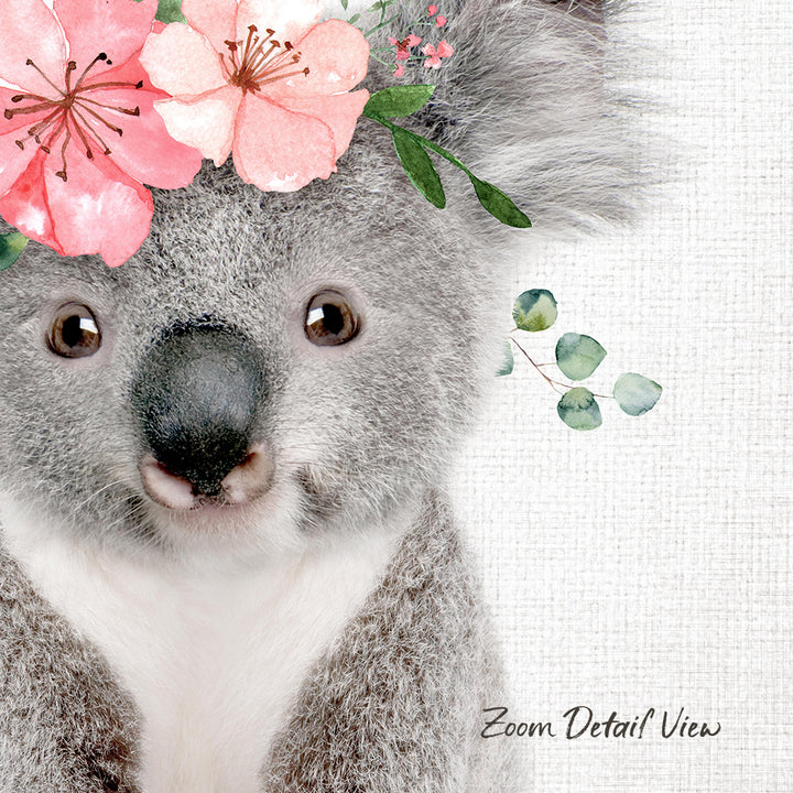 A close-up of a koala bear with a floral headpiece on its head, set against a white background.