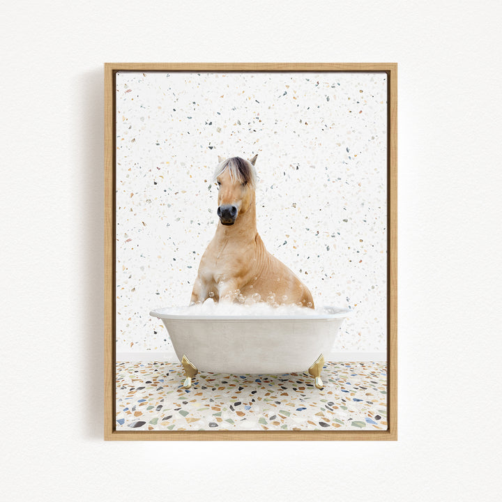 A light brown horse is sitting in a white bathtub filled with water, surrounded by a speckled tiled floor.