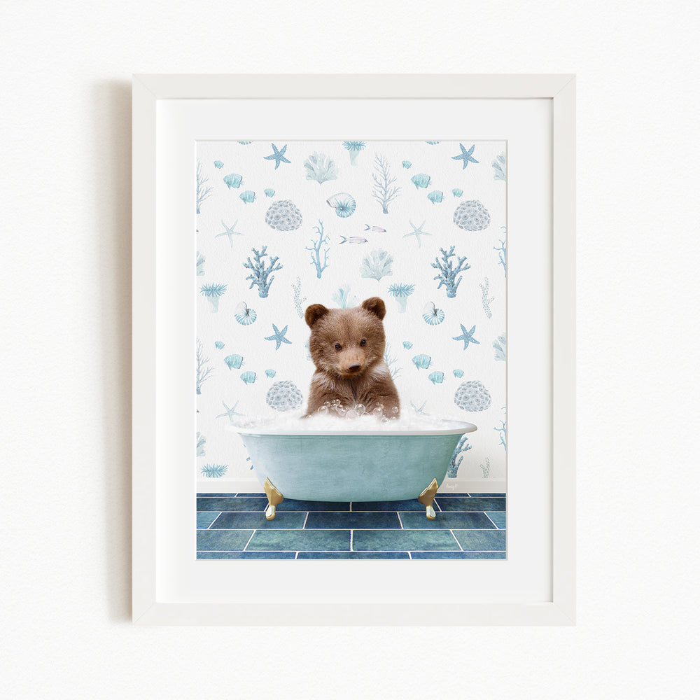 A cute brown bear sitting in a blue bathtub filled with bubbles, surrounded by a blue and white ocean-themed wallpaper.