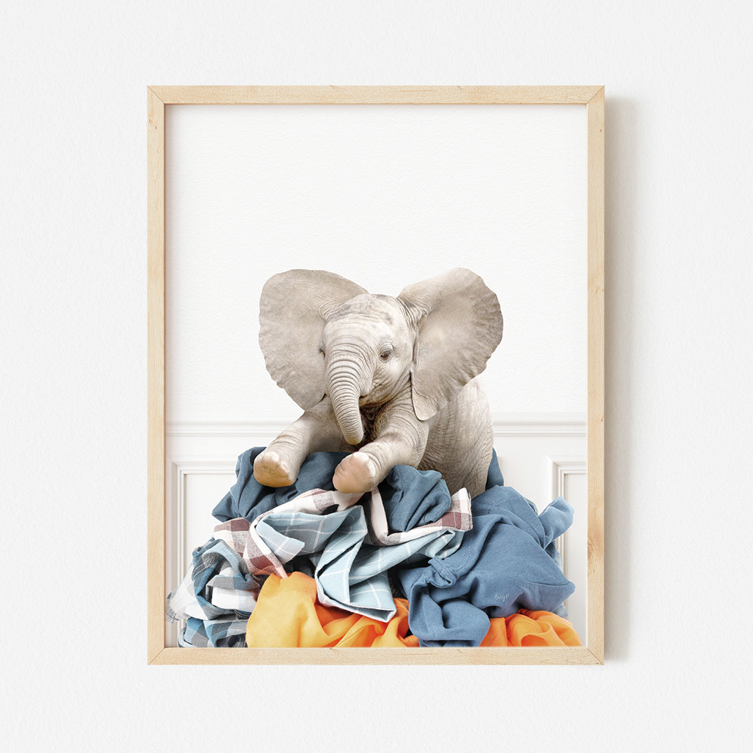 a stuffed elephant sitting on top of a pile of clothes