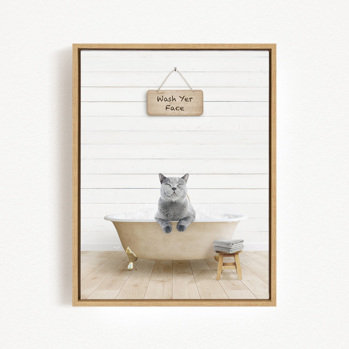 A gray cat sitting in a bathtub, with a wooden sign above that says "Wash Yer Face".