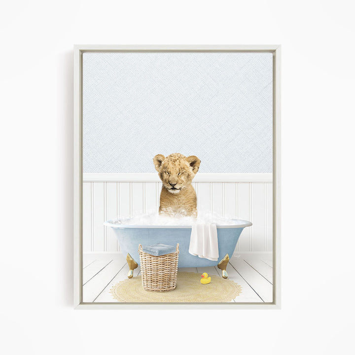 A young lion cub sitting in a blue bathtub filled with water, surrounded by a yellow rubber duck and a basket.