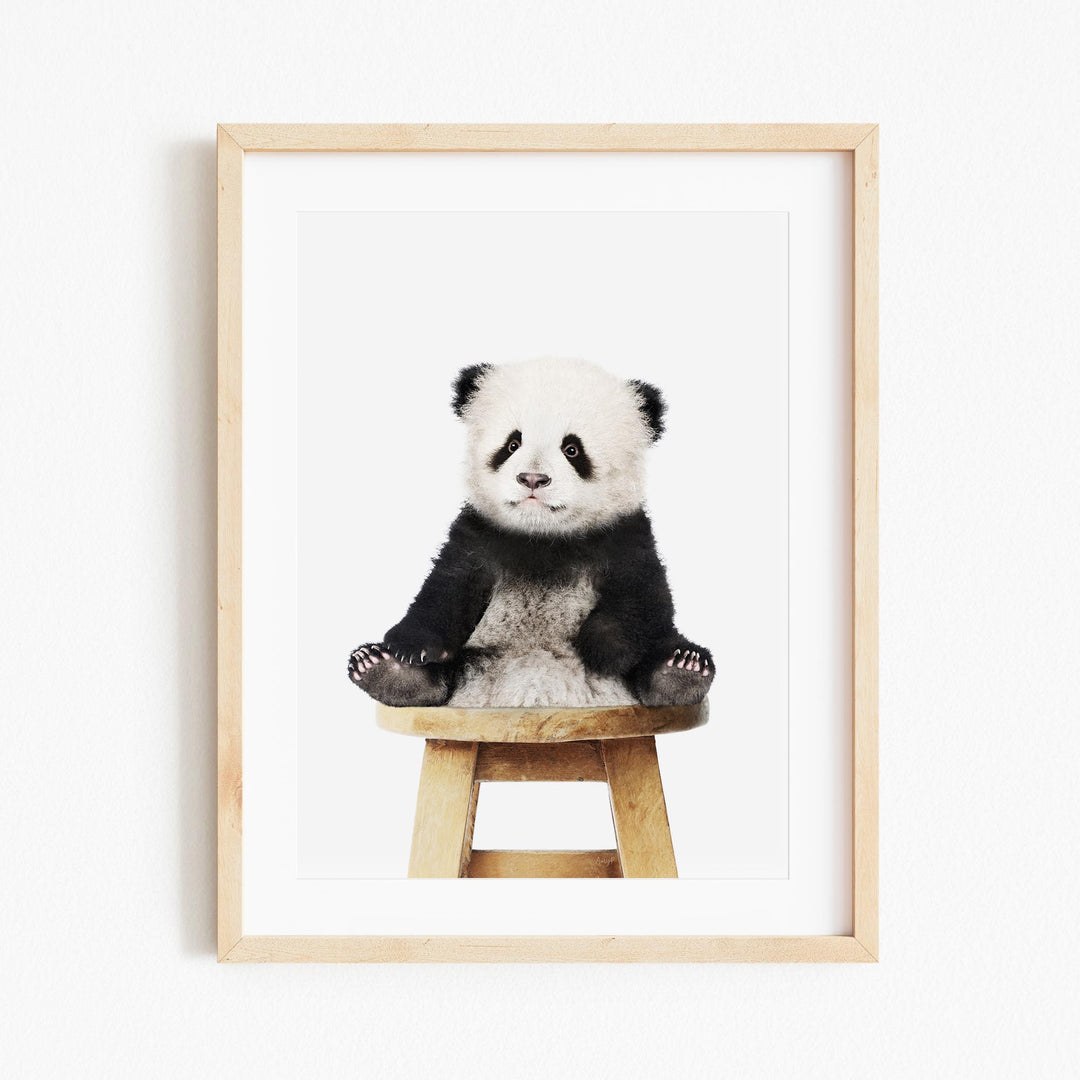 a panda bear sitting on top of a wooden stool