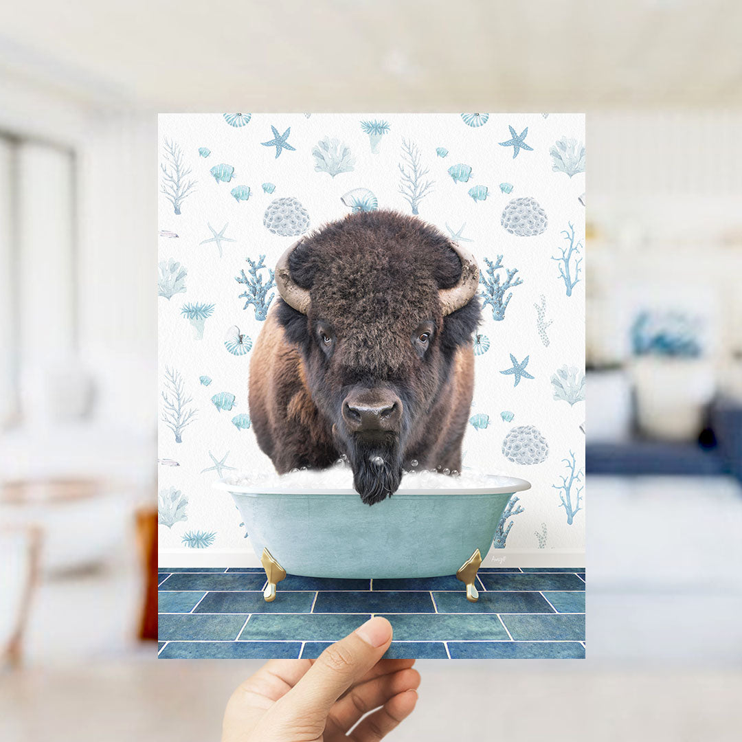 A hand is holding up a printed image of a bison in a bathtub, surrounded by a blue and white floral pattern.