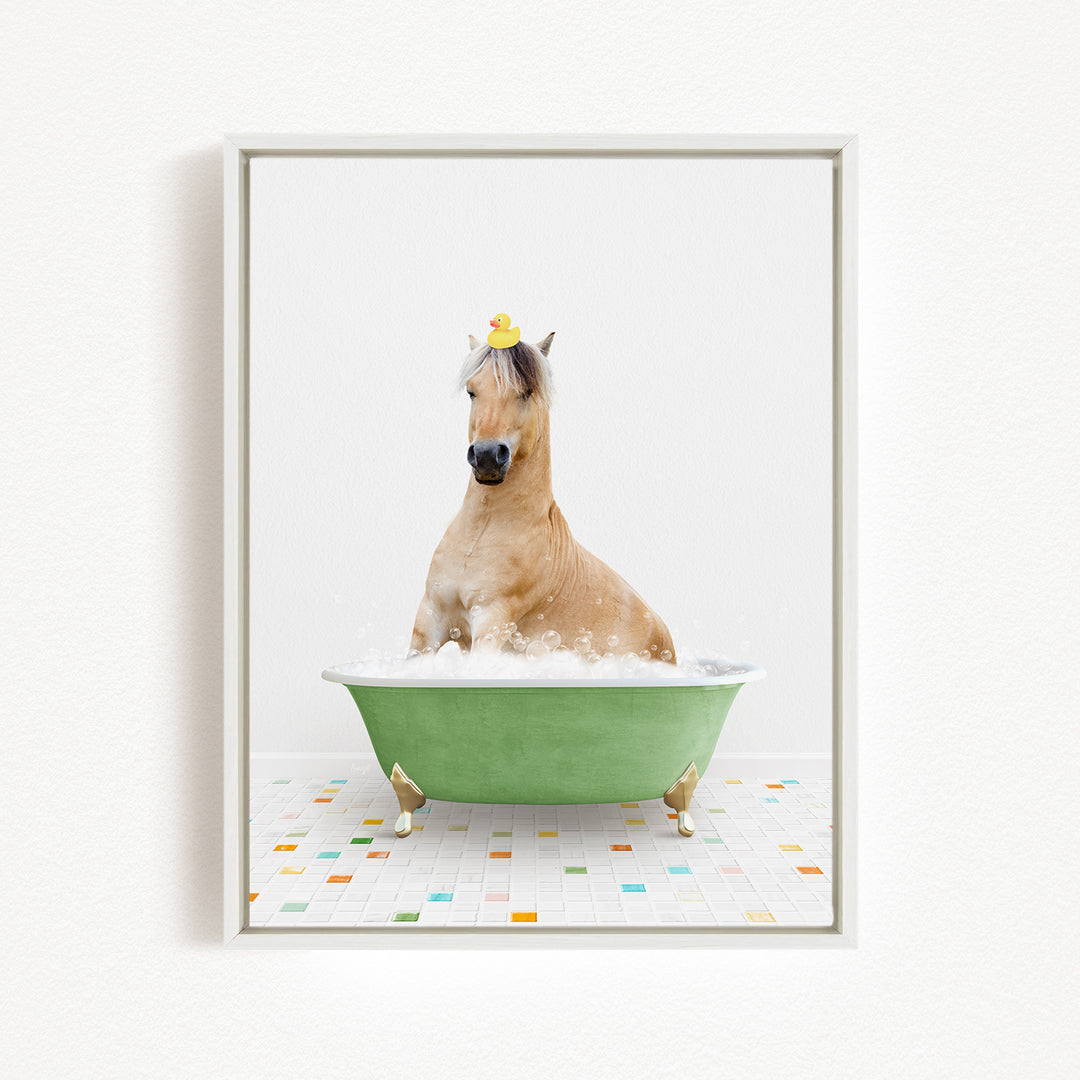 A light brown horse is sitting in a green bathtub filled with bubbles, wearing a yellow rubber duck on its head.