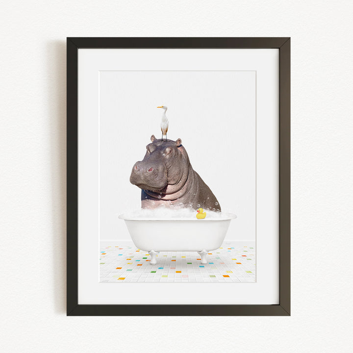 A framed image depicting a hippopotamus sitting in a bathtub, with a bird perched on its head.