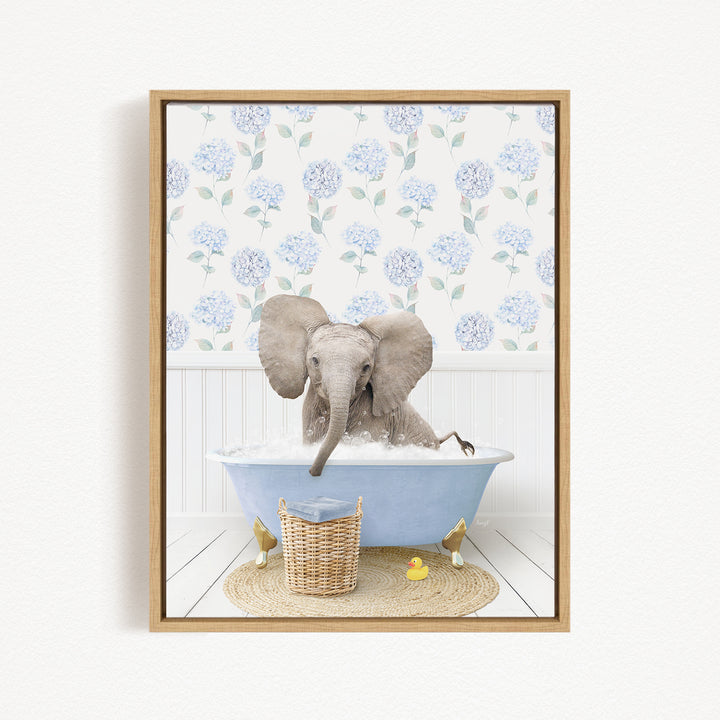 A gray elephant is sitting in a blue bathtub filled with water, surrounded by a wicker basket and rubber duckies.