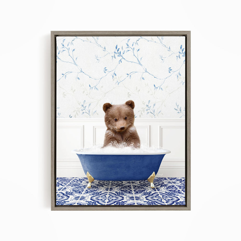 A cute brown bear sitting in a blue bathtub filled with bubbles, surrounded by a blue and white patterned rug.
